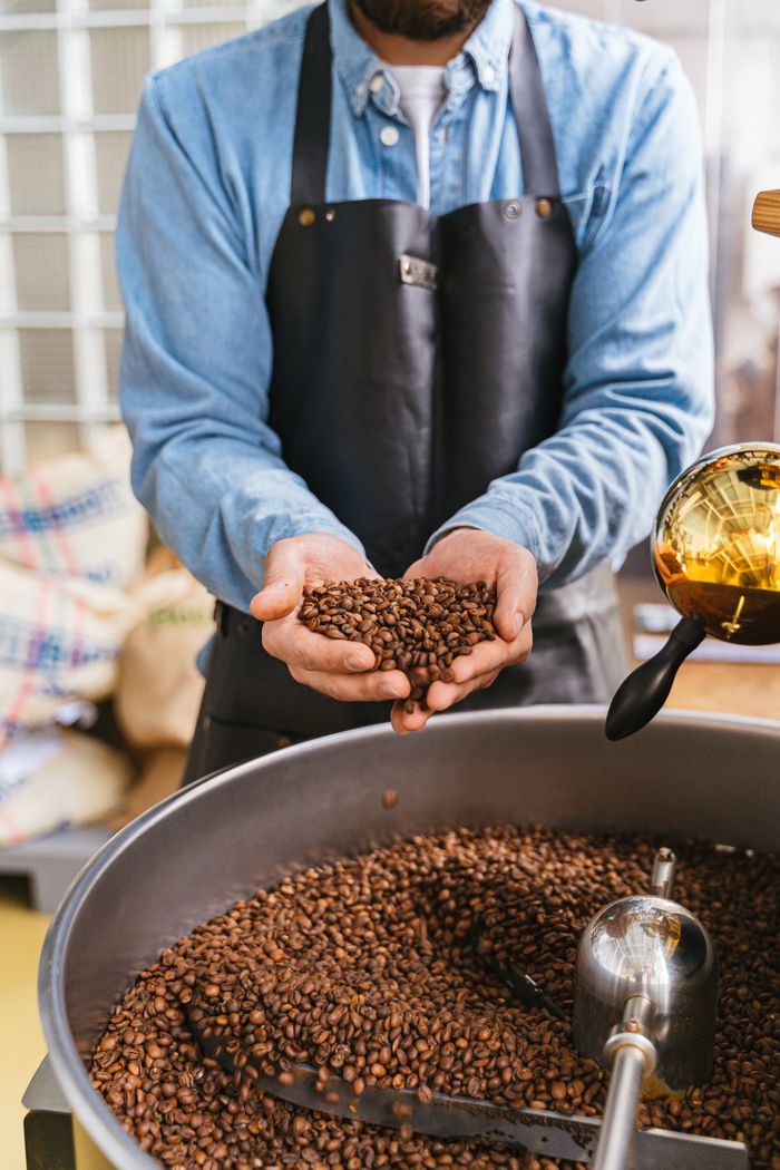 Crafting Captivating Headlines: Your awesome post title goes here Master coffee roaster holding freshly roasted beans for quality inspection.